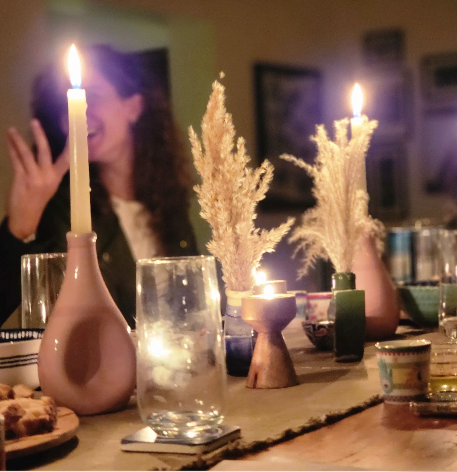 A shared candlelit dinner table with Ové ceramic candlesticks and glasses